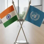Crossed desk flags of India and the United Nations on a table stand.