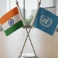 Crossed desk flags of India and the United Nations on a table stand.